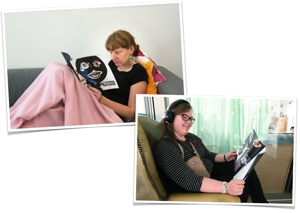 Två tjejer som sitter i en varsin soffa och läser magasinet. Ena tjejen har en rosa filt över knäna.