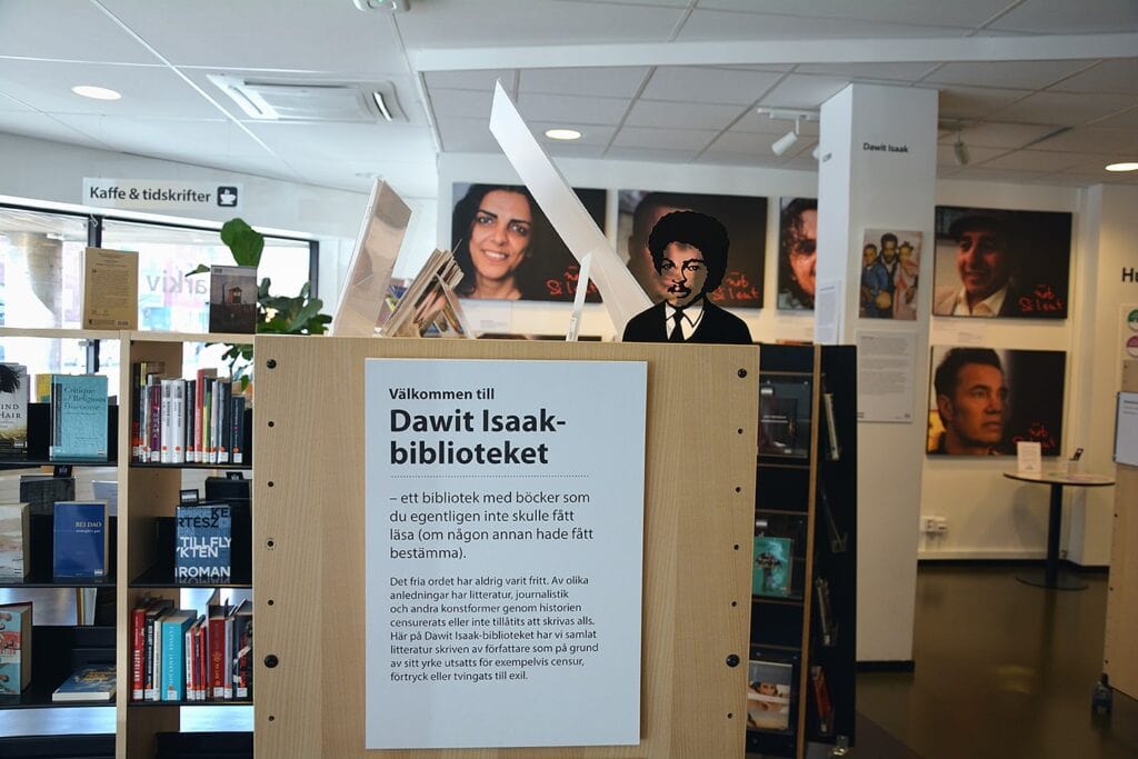På gaveln av en bokhylla sitter en vit rektangulär skylt uppe med som hälsar välkommen till Dawit Isaak-biblioteket. 