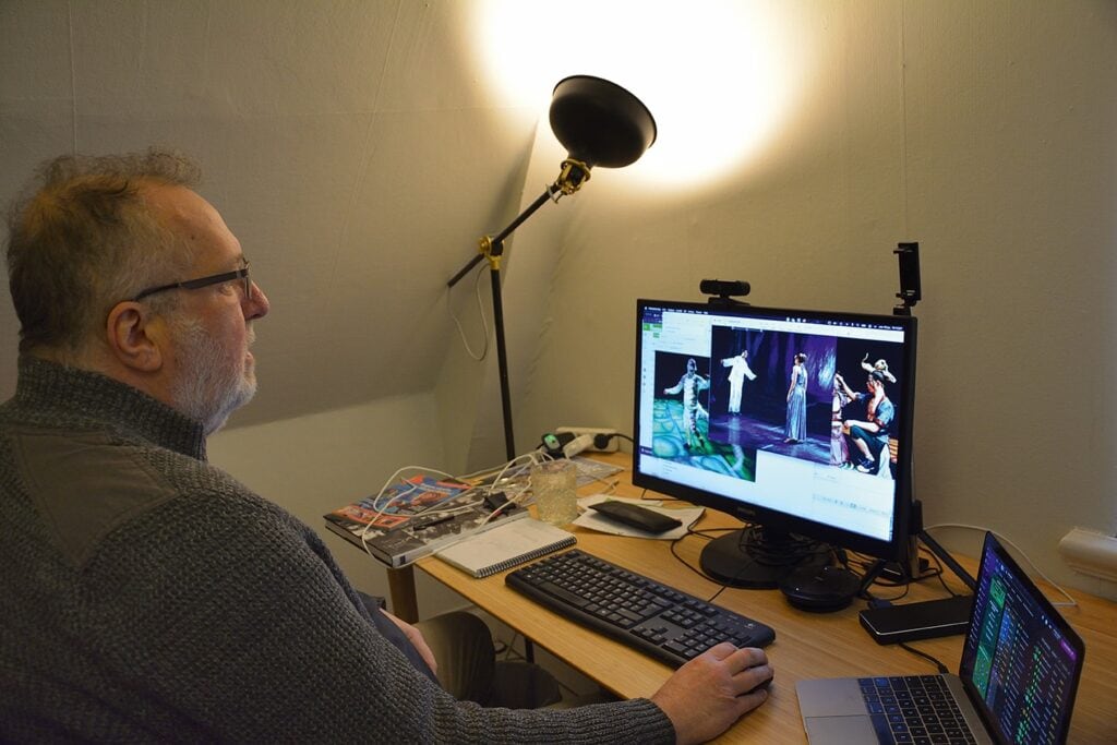 Kjell sitter vid sin dator och kollar på foton som visas på en bildskärm.