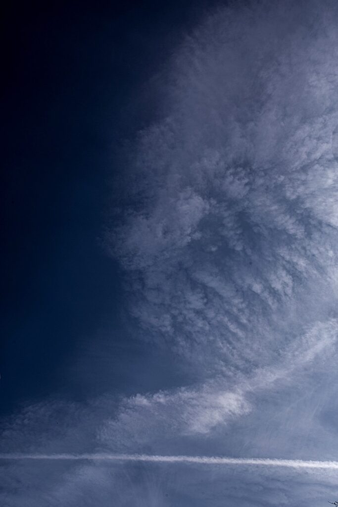 En mörkblå himmel med en molnslöja som breder ut sig likt en fjärilsvinge sett från sidan eller med utslagna vingar.