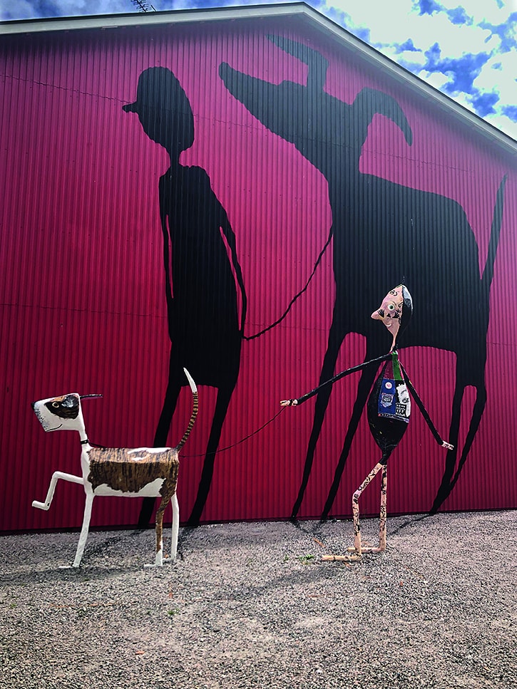 Konstverket består av en lekfull skulptur med en person som är ute och går efter sin hund, samt en målning mot en fasad som föreställer deras skuggor, men där positionerna på hunden och personen bytt plats.