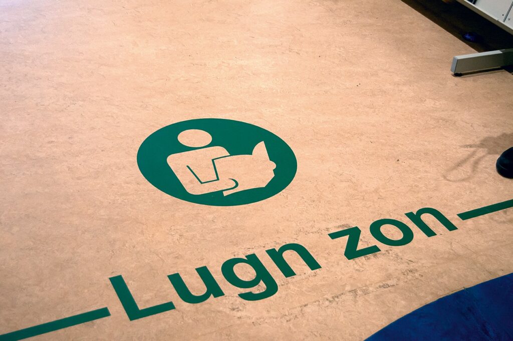 På golvet en rund symbol med en person som håller en uppslagen bok och under texten ”Lugn Zon”.