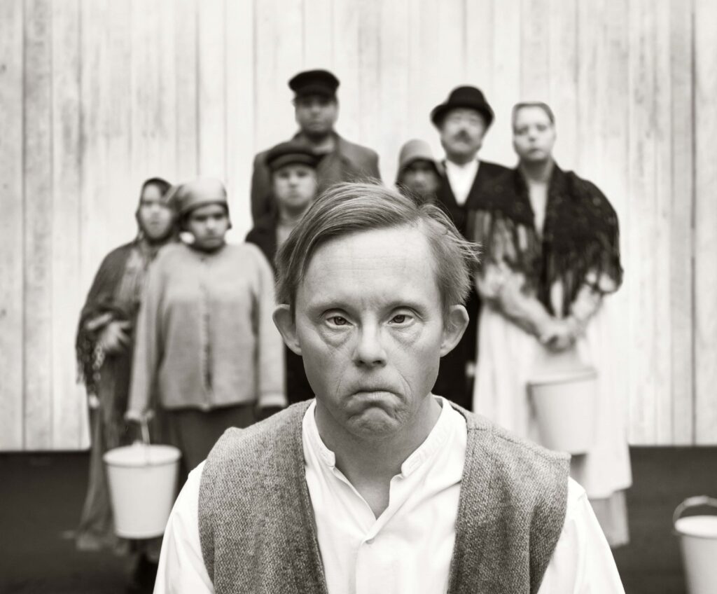 Svartvitt foto från föreställningen ”Den enfaldige mördaren” på Moomsteatern 2019. Niclas Lendemar i halvfigur som sin karaktär Sven.
