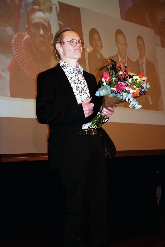 Niclas Lendemar på scenen vid prisutdelningen. Han står framför den stora bildskärmen med foton av honom.